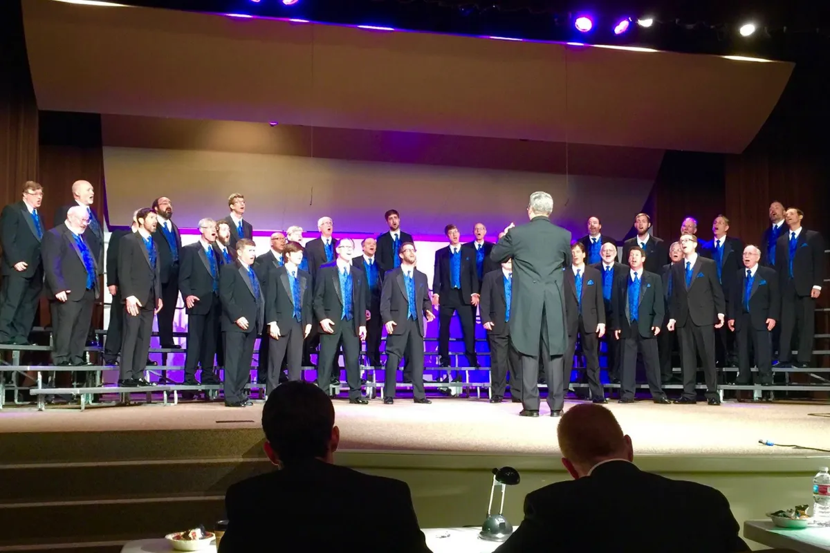 Ted directing a men's chorus on stage